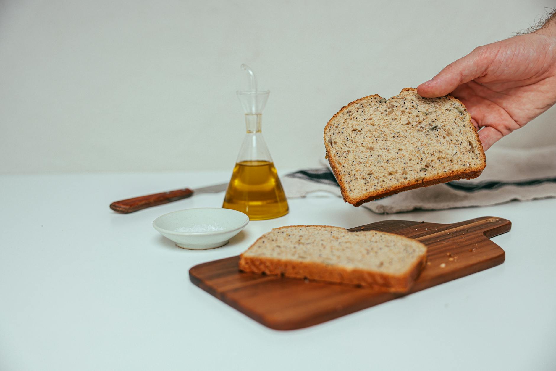 a person holding a slice of bread beside a dispenser with yellow liquid